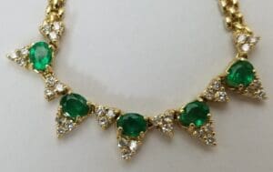 Gold necklace with emeralds and diamond clusters.