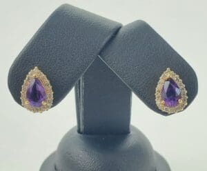 Gold and amethyst teardrop earrings display.