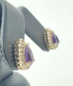 Gold earrings with purple gemstones on display.