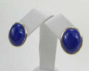 Gold-rimmed earrings with blue stones.