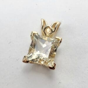 Gold pendant with a square gemstone.