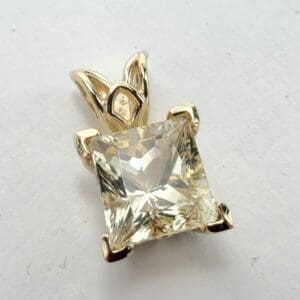 Gold pendant with square-cut clear gemstone.