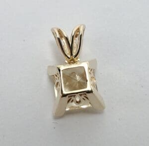 Gold pendant with a square gemstone.