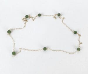 Gold chain necklace with green beads.