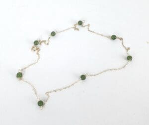 Gold chain necklace with green beads.