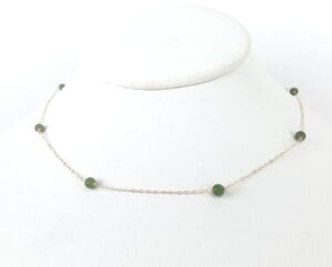 Gold chain necklace with green beads.