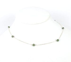 Silver necklace with green beads on display.