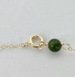 Gold chain with green bead clasp.