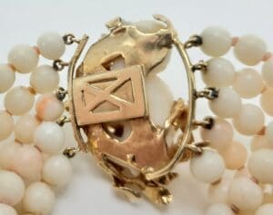 Gold clasp with white beaded bracelet.