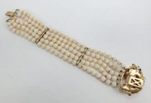 White beaded bracelet with gold clasp.