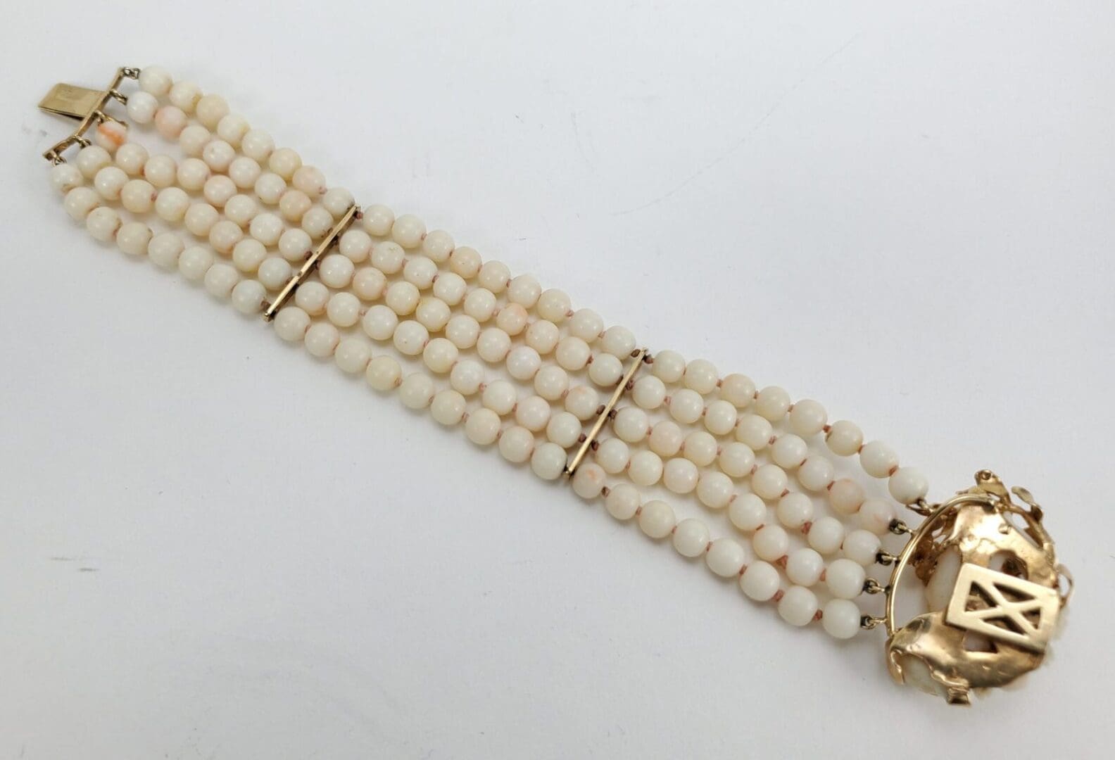 White beaded bracelet with gold clasp.