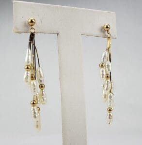 Gold and pearl dangling earrings on display.