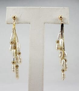 Gold and pearl drop earrings on display.