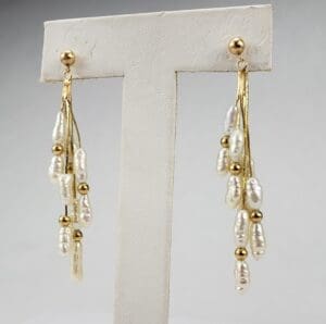 Gold and pearl dangling earrings on display.