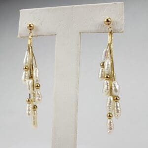 Gold and pearl dangling earrings on display.
