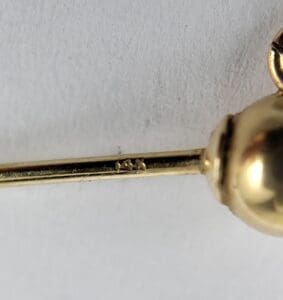 Close-up of gold pin with markings.