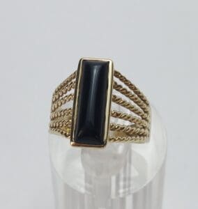 Gold ring with black rectangular stone.