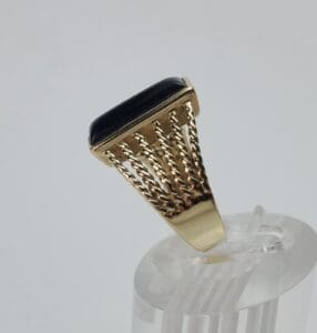Gold ring with black stone on display.