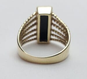 Gold ring with black rectangular stone.