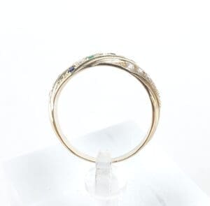 Gold ring with gemstones on clear stand.