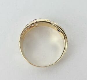Gold ring with embedded gemstones, plain background.