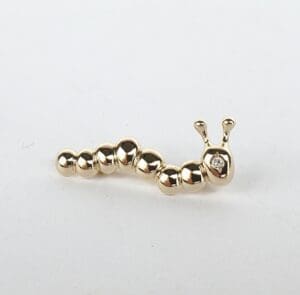 Gold caterpillar-shaped pin on white background.