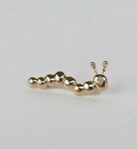 Gold caterpillar-shaped earring with diamond accent.