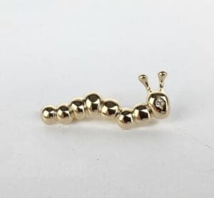 Gold caterpillar-shaped jewelry piece with diamond.
