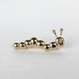 Gold caterpillar-shaped jewelry piece with diamond.