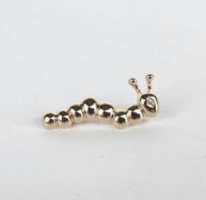 Gold caterpillar-shaped brooch on white background.