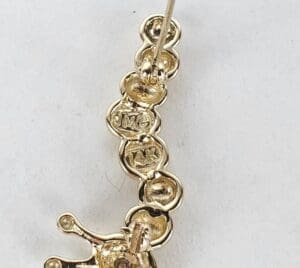 Gold earring with engraved markings close-up.