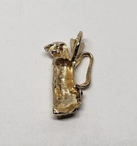 Gold-toned golf bag charm on white background.