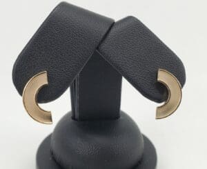 Gold crescent-shaped earrings on black stand.
