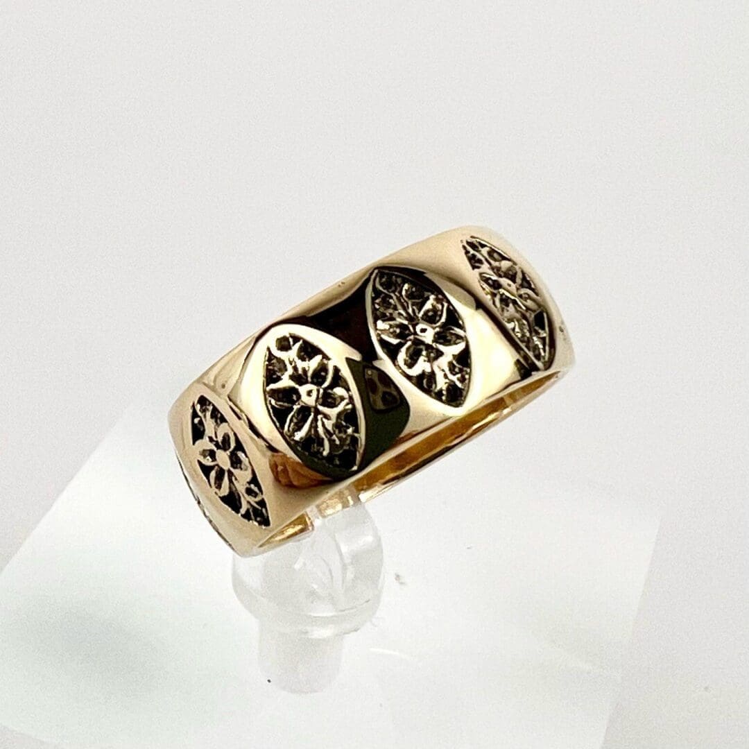 Gold ring with intricate black floral design.