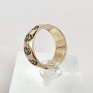 Gold ring with engraved patterns displayed.