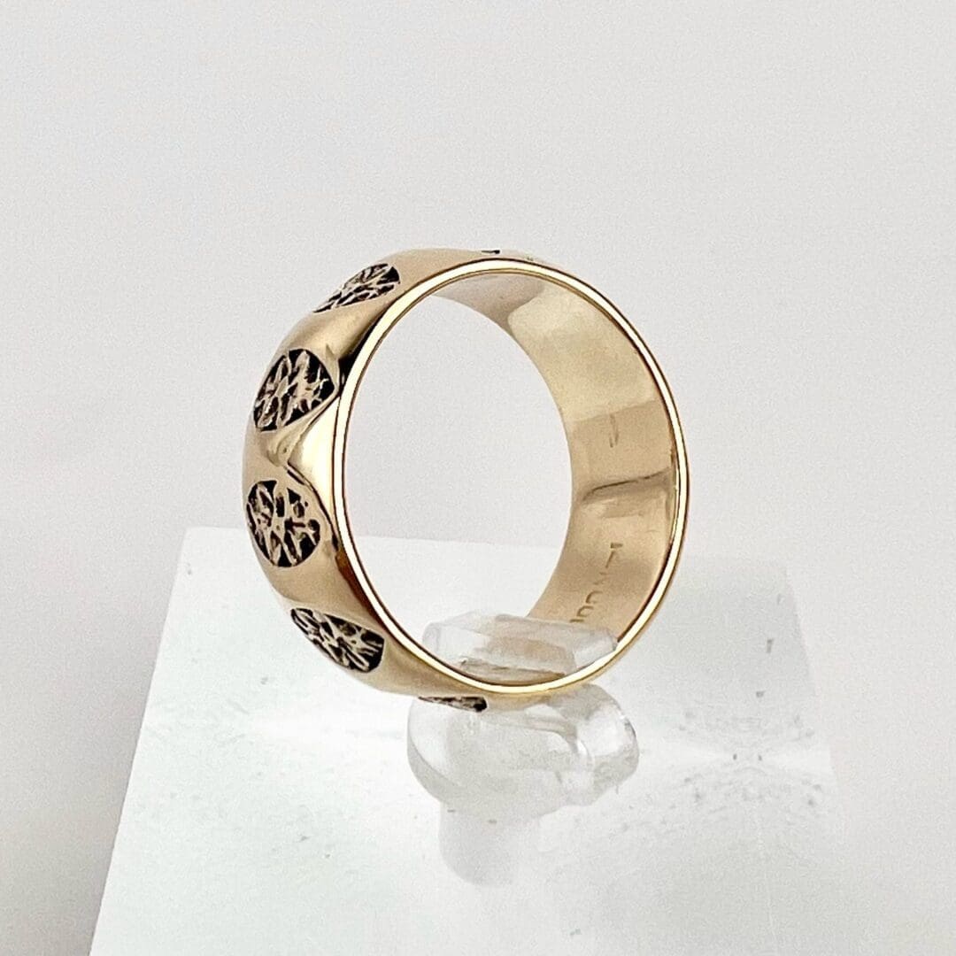 Gold ring with engraved patterns displayed.