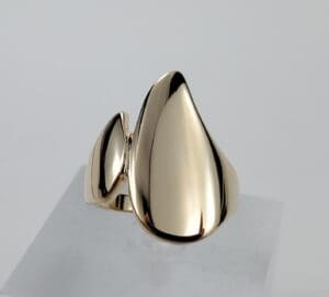 Gold abstract-shaped ring on display stand.
