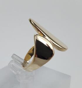 Gold abstract ring on clear stand.