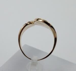 Gold ring on white display stand.