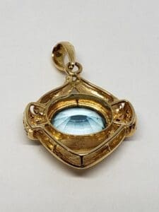 Gold pendant with blue gemstone centerpiece.
