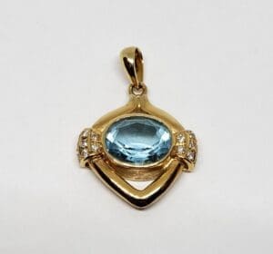Gold pendant with blue gemstone and diamonds.