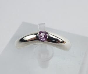 Silver ring with purple gemstone on display.