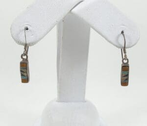 Colorful dangle earrings on white display stand.
