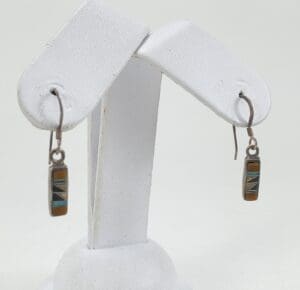 Colorful rectangular earrings on display stand.