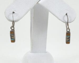 Geometric stone inlay earrings on display stand.