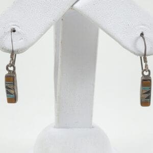 Geometric stone inlay earrings on display stand.
