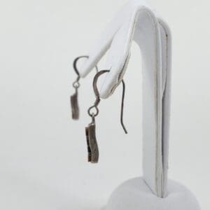 Silver earrings on a white display stand.