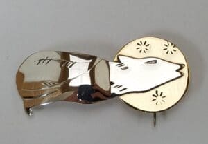 Silver wolf brooch with golden accents.