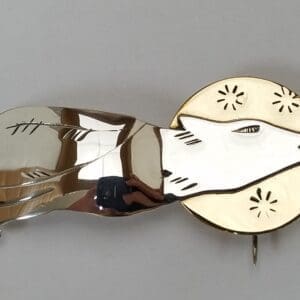 Silver wolf brooch with golden accents.