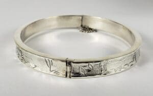 Silver bangle with geometric engraved patterns.